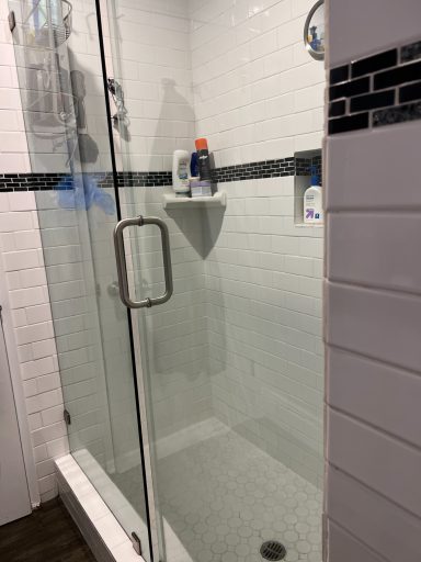 Modern glass shower enclosure with a small shelf for toiletries.